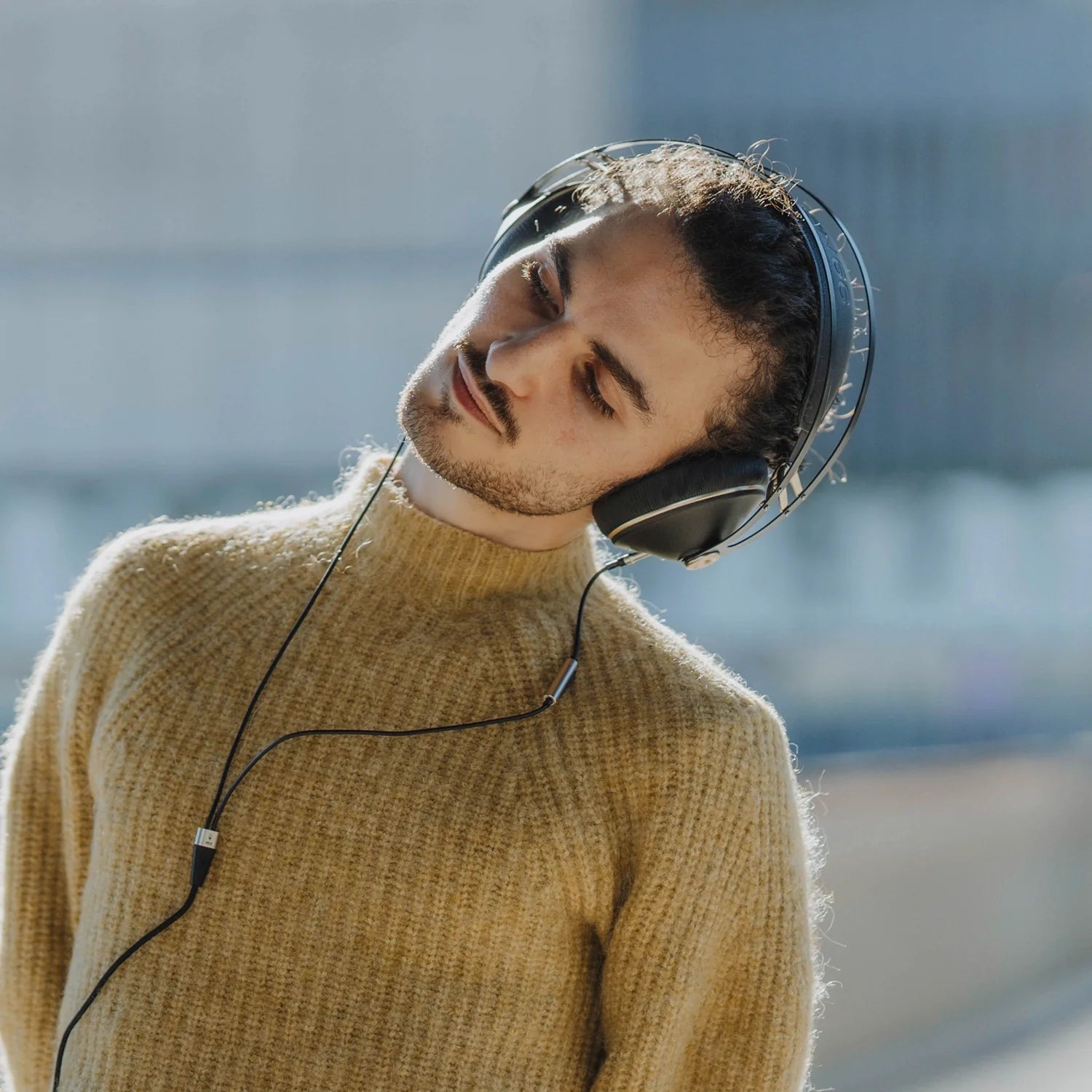 Meze Audio 109 PRO best open back audiophile headphones worn by a man with long hair outside